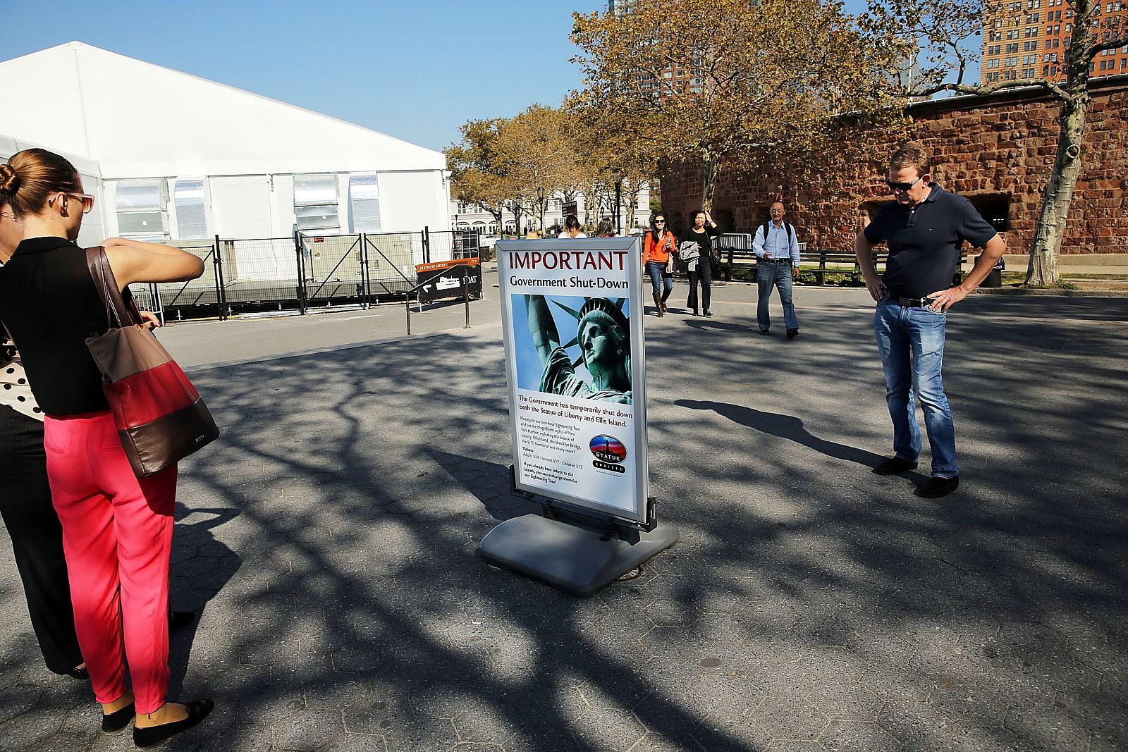 Turistas contemplan el cartel que informa del cierre de la Estatua de la Libertad, en Nueva York, debido al 'shutdown'
