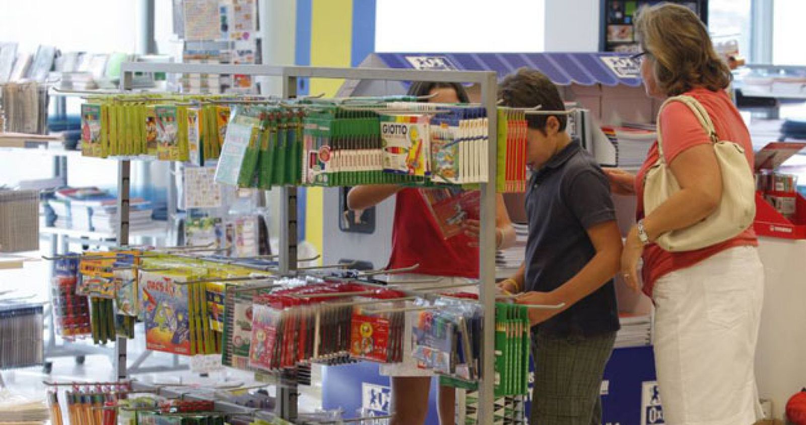 Una mujer mira el material escolar en una tienda junto a dos niños