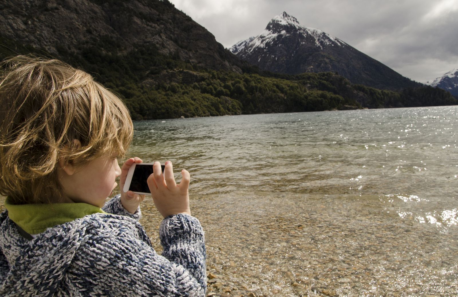Un niño jugando con el móvil en medio de la naturaleza.