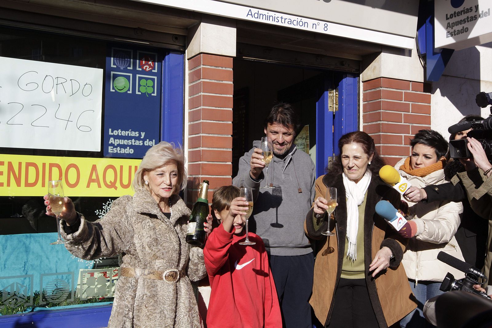 La lotera Maria Luisa celebra con una familia agraciada con el Gordo a la entrada de su administración, la número 8 de Leganés