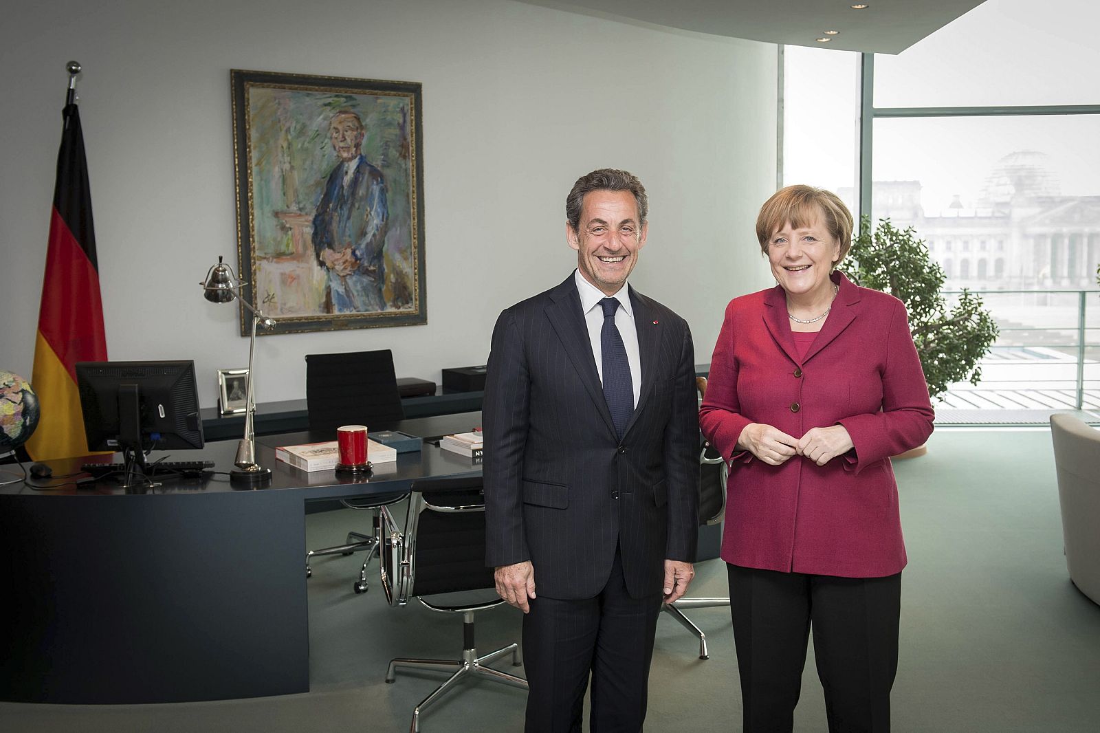 Handout photo of German Chancellor Merkel posing for a picture with former French President Sarkozy at the chancellery in Berlin
