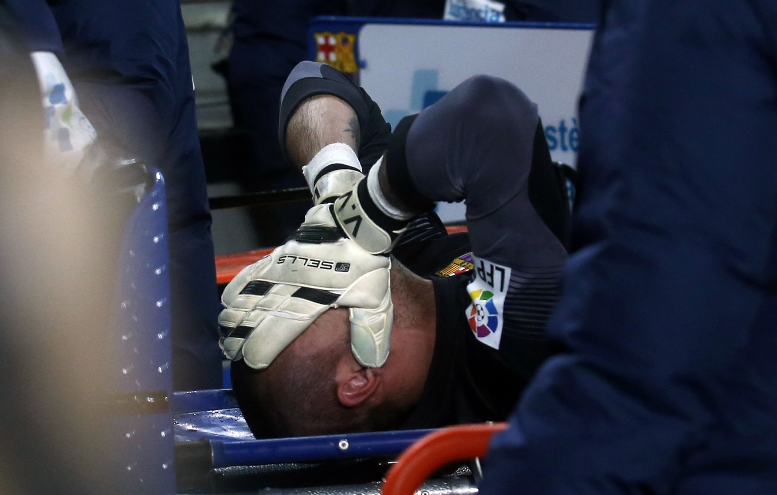 Barcelona's goalkeeper Victor Valdes covers his face as he is carried off on a stretcher after picking up an injury against Celta Vigo during their La Liga soccer match at Camp Nou stadium in Barcelona