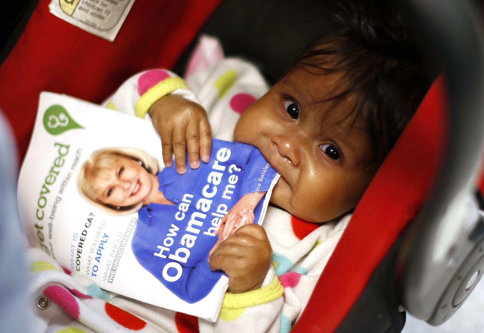 Hazel Garcia chews a pamphlet at a health insurance enrollment event in Cudahy, California