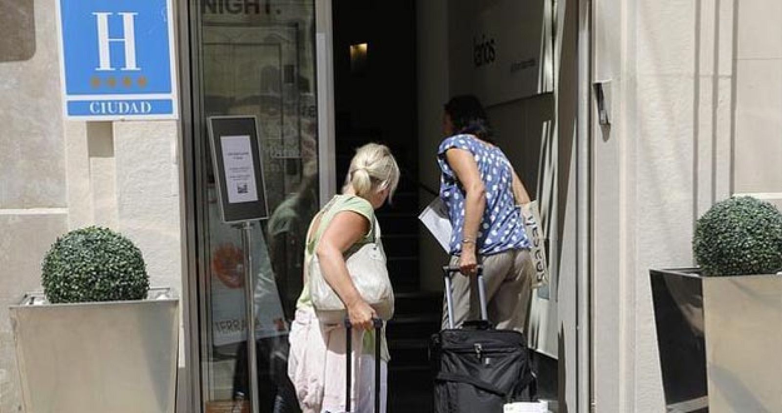 Dos turistas se asoman a la entrada de un hotel