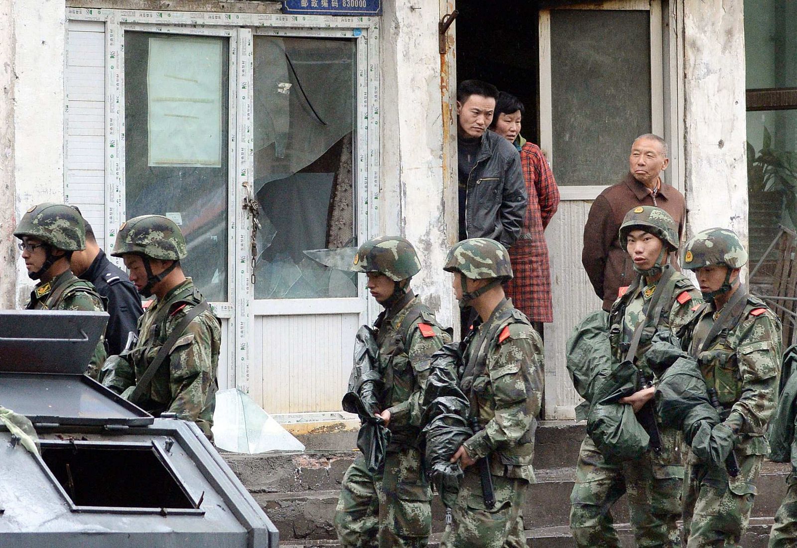 Paramilitary policemen patrol past a building, where a window was damaged by an explosion in Urumqi on Thursday, in the Xinjiang Uighur Autonomous Region