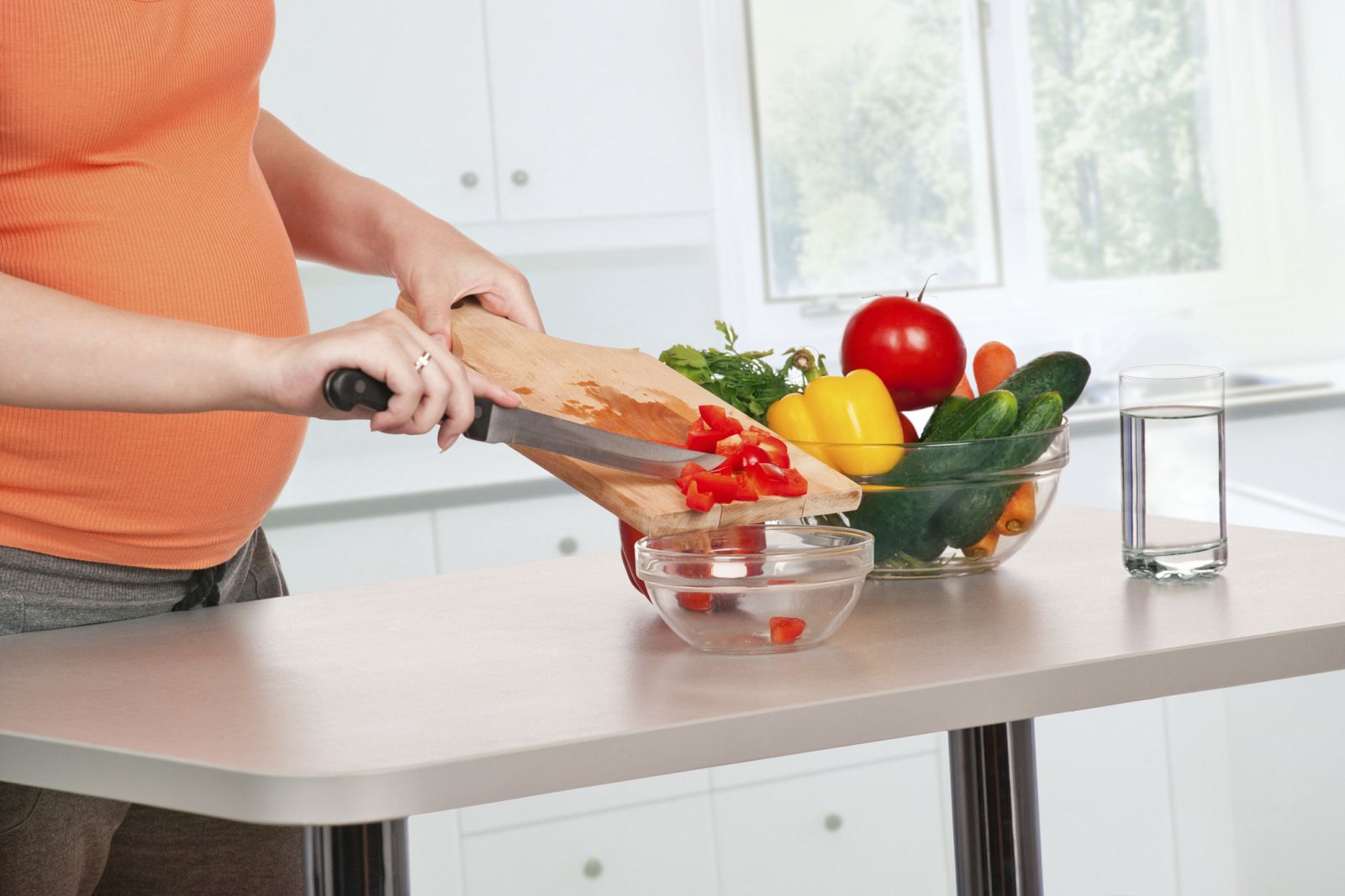Mujer embarazada cocinando verduras.