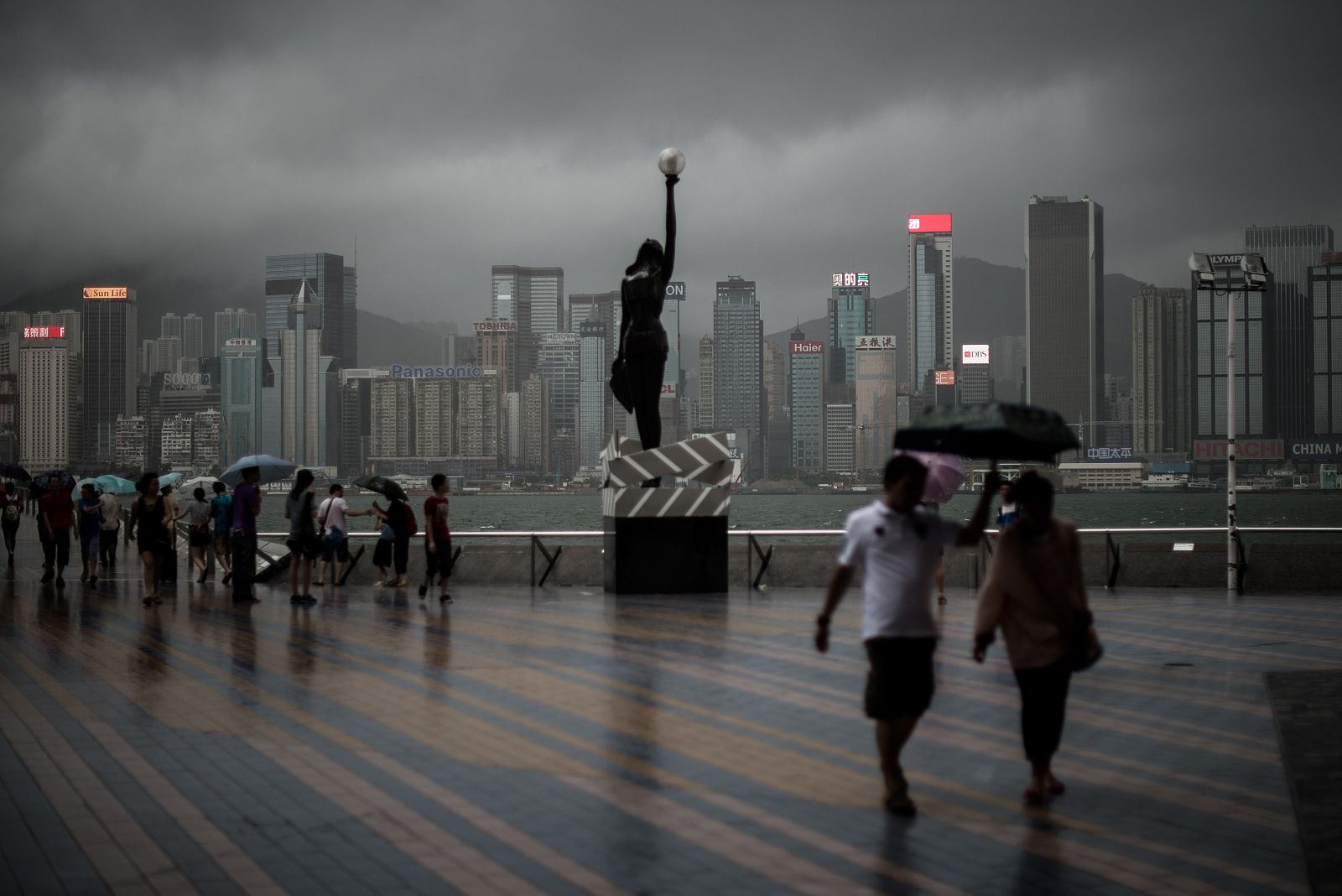 Ciudadanos de Hong Kong andando bajo la tormenta provocada por el superifón Rammasun