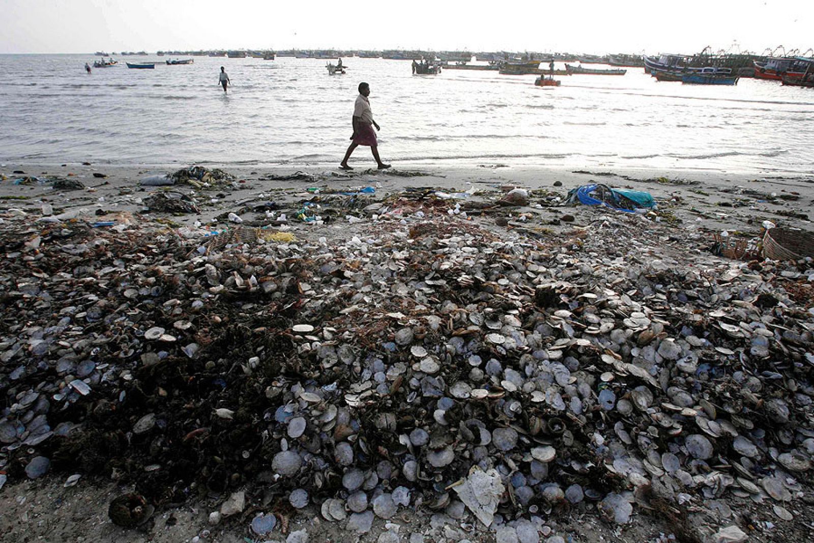 Un pescador camina entre la basura amontonada en la orilla en laciudad meridional india de Rameswaram.
