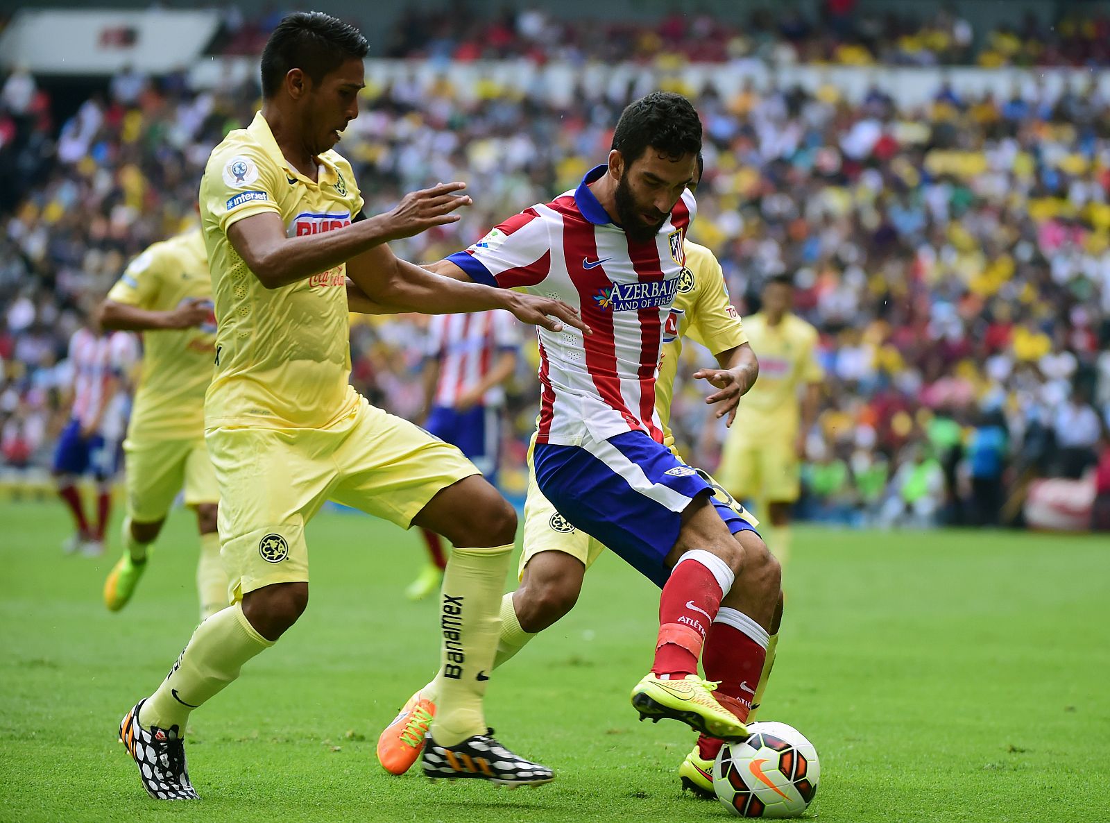 El jugador del Atlético de Madrid Raúl García pelea la bola con Juan Carlos Valenzuela, del América durante un momento del partido de la copa EuroAmericana.