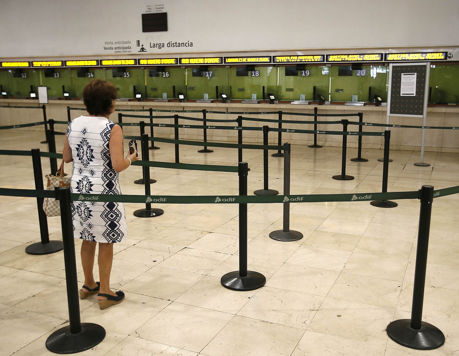 A woman looks at empty ticket booths in Sants railway station during a nationwide strike by rail workers in Barcelona