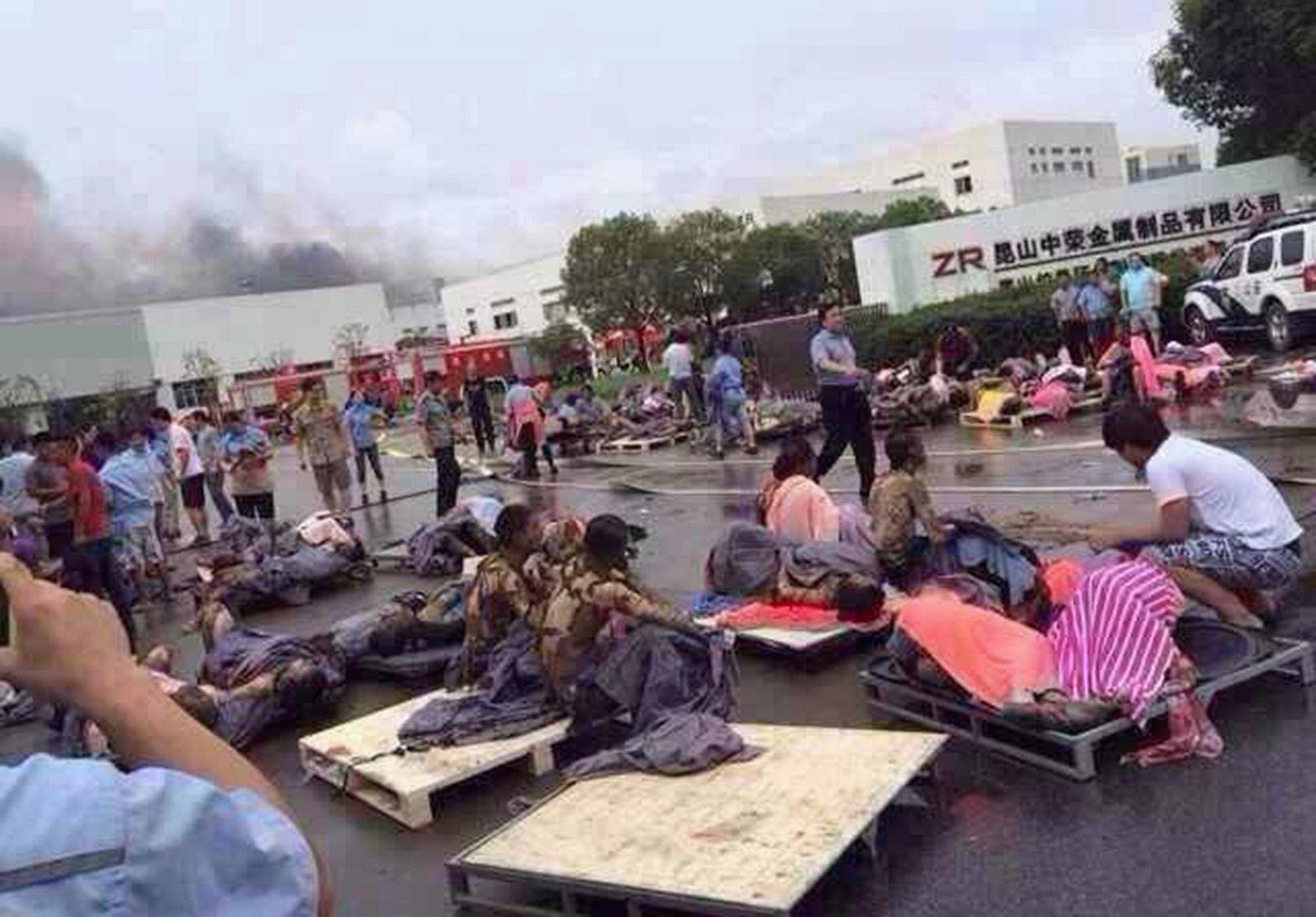 Rescuers help the victims of an explosion at the gate of a factory in Kunshan