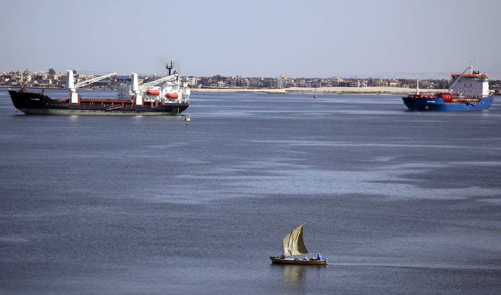 File photo of a fisherman traveling on a boat near container ships in the Suez Canal