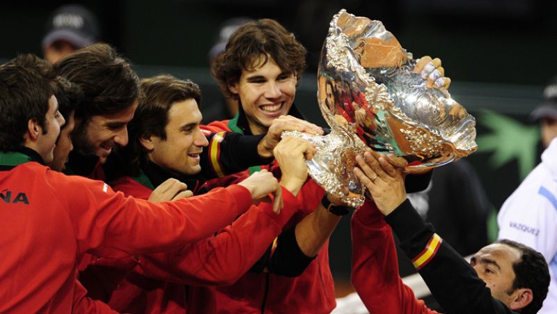 El rey Juan Carlos ha entregado al capitán del equipo español de Copa Davis, Albert Costa, el trofeo de campeón de esta competición, que consiguen por quinta vez.