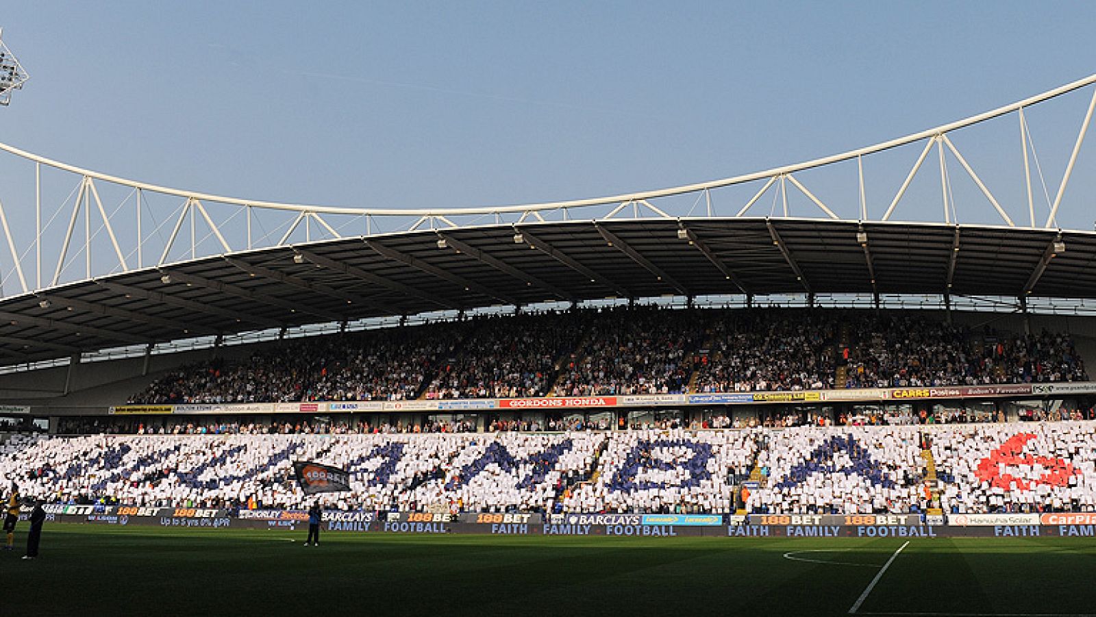 Los aficionados del Bolton Wanderers desplegaron hoy un gran mosaico en las gradas del Reebok Stadium para rendir homenaje al centrocampista de origen congoleño Fabrice Muamba, que la pasada semana sufrió un paro cardíaco durante un encuentro frente