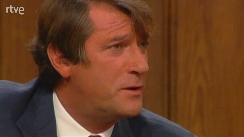 Imagen cercana de Alfonso Cabeza hablando; viste chaqueta azul marino y camisa blanca; fondo de madera con logo RTVE.