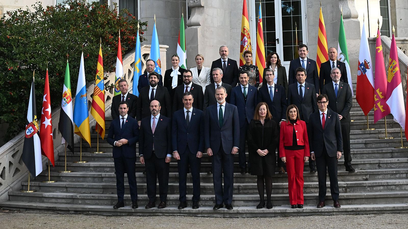 Foto oficial de la Conferencia de Presidentes: Felipe VI y Pedro Sánchez, junto a otros representantes políticos en traje formal, posan en una escalinata con banderas españolas y autonómicas.