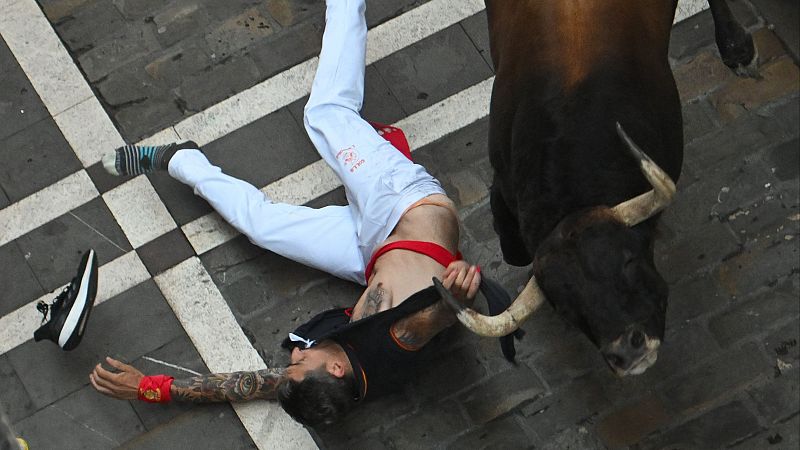 Tercer encierro de San Fermín 2025: Un toro arrastra a un corredor por la camiseta durante varios metros | Ver