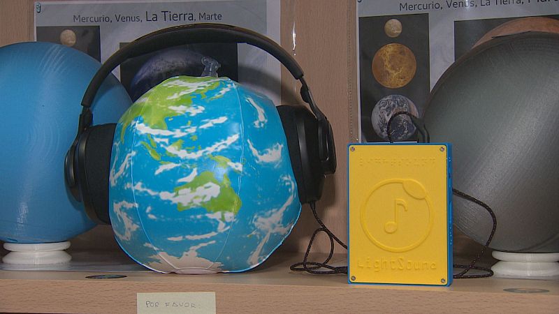 Estación interactiva con globo terráqueo, auriculares y dispositivo "LightSound" para experimentar fenómenos astronómicos mediante el sonido, ideal para personas con discapacidad visual.