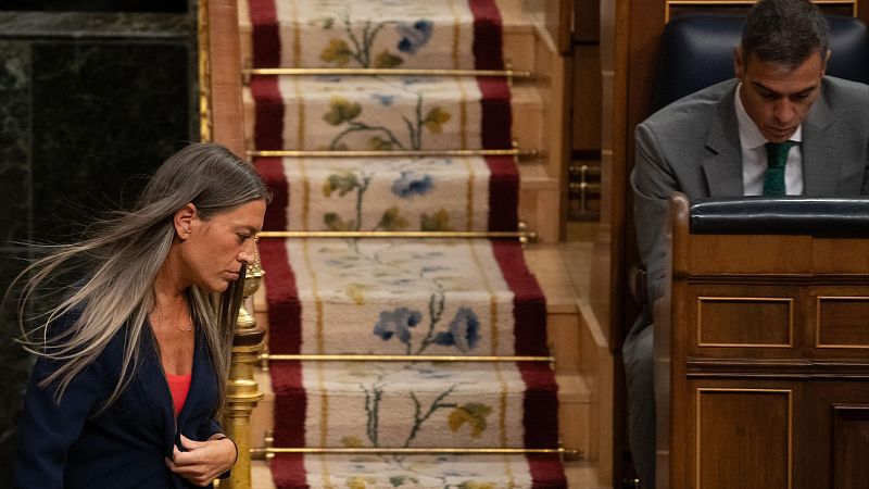 Pedro Sánchez revisa papeles en su escaño mientras Míriam Nogueras camina por el hemiciclo del Congreso de los Diputados.