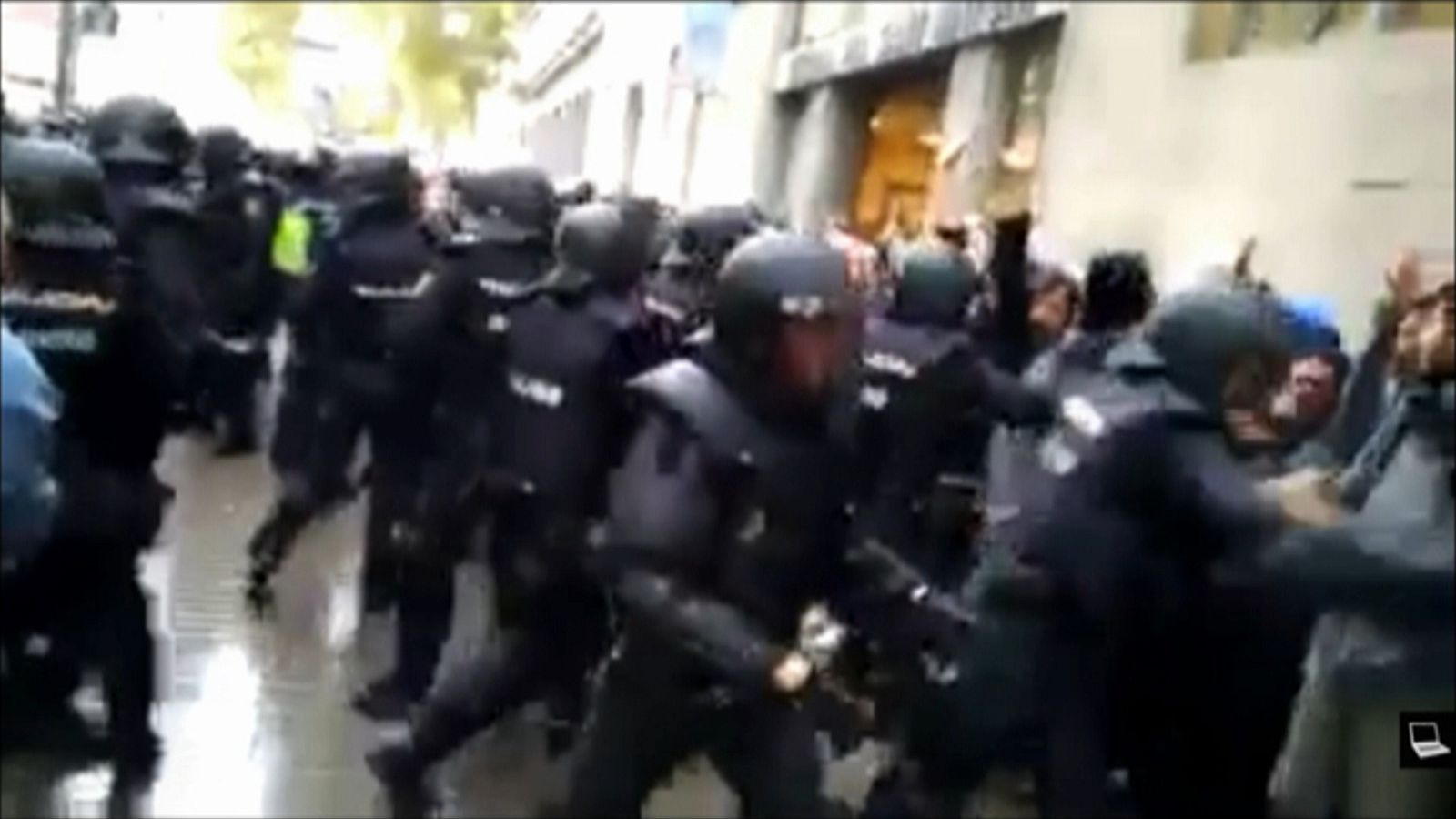 Un agente de policía judicial da una patada a un hombre mayor en el suelo