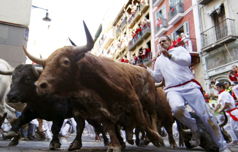  Un joven ha protagonizado la carrera más emocionante de las fiestas en la curva de Estafeta, donde ha corrido en paralalelo a los toros y cercado por el vallado, librándose por poco de la cornada. 