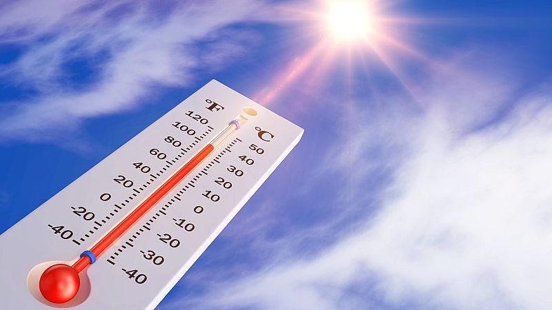 Un termómetro bajo el cielo azul y el destello del sol