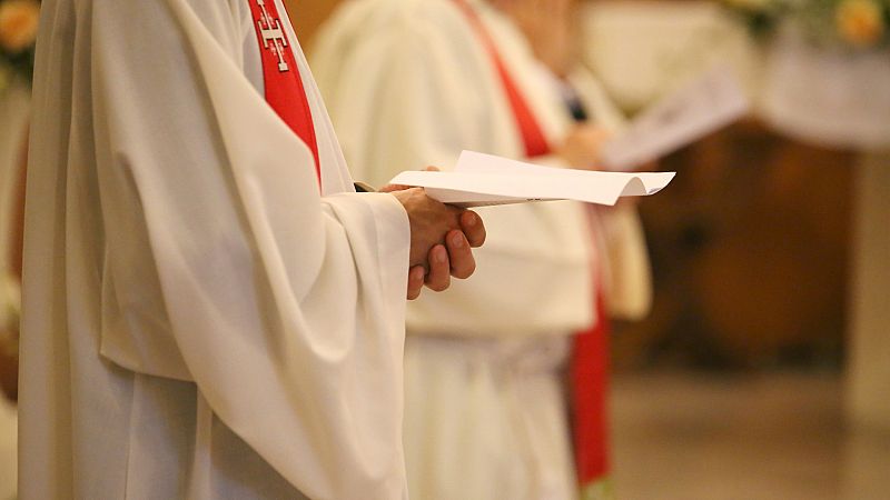 Un sacerdote sostiene un folio durante una misa