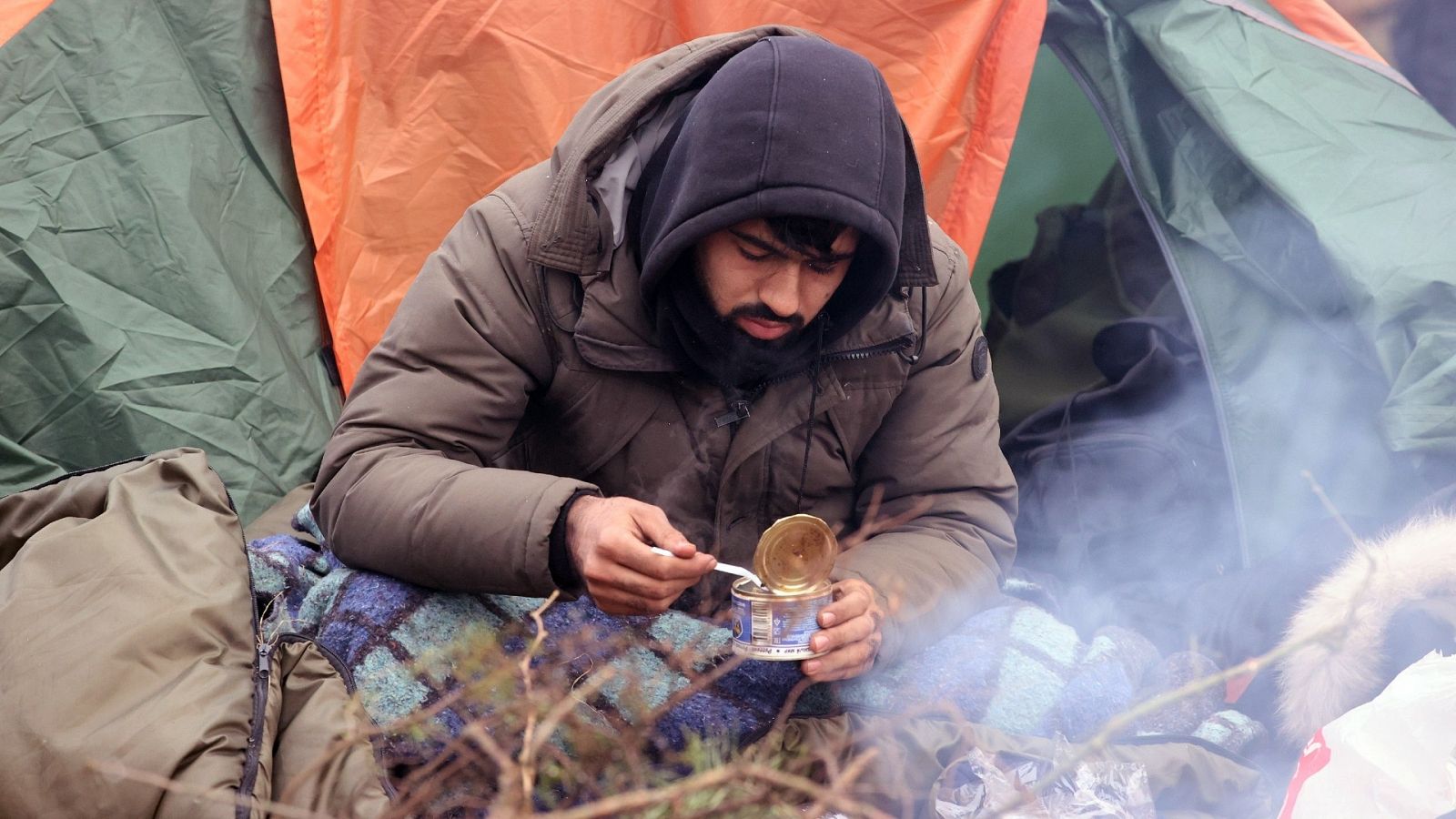 Un hombre come de una lata de conservas en el campamento de refugiados