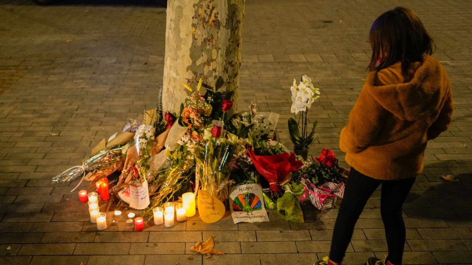 Una niña flores y velas en memoria por las personas fallecidas