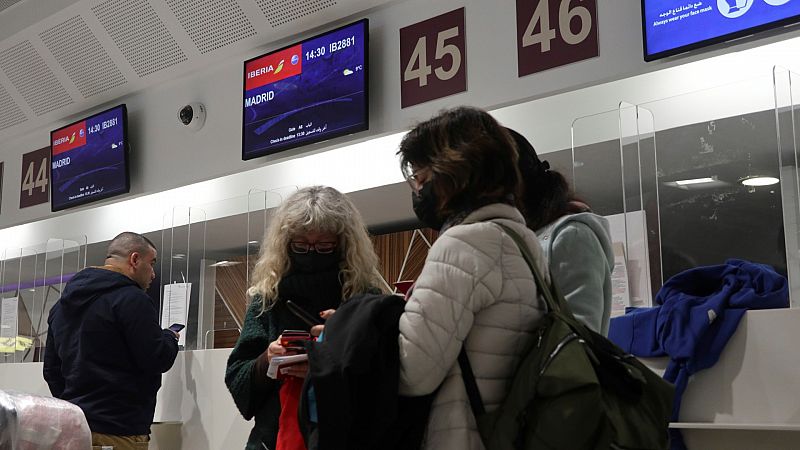 Varias personas bajo el monitor con la información correspondiente al primer vuelo de repatriación